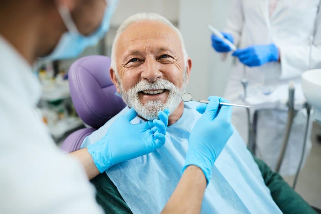 all-on-4 vs dentures Happy senior man having dental treatment at dentist's office.